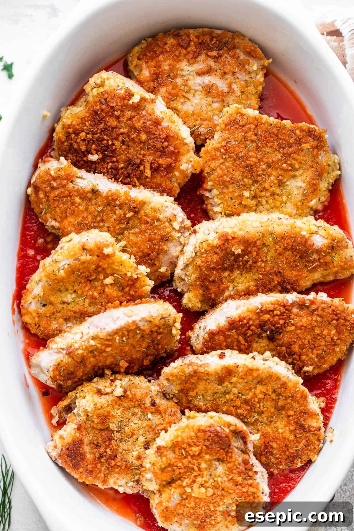breaded pork medallions arranged in a white baking dish