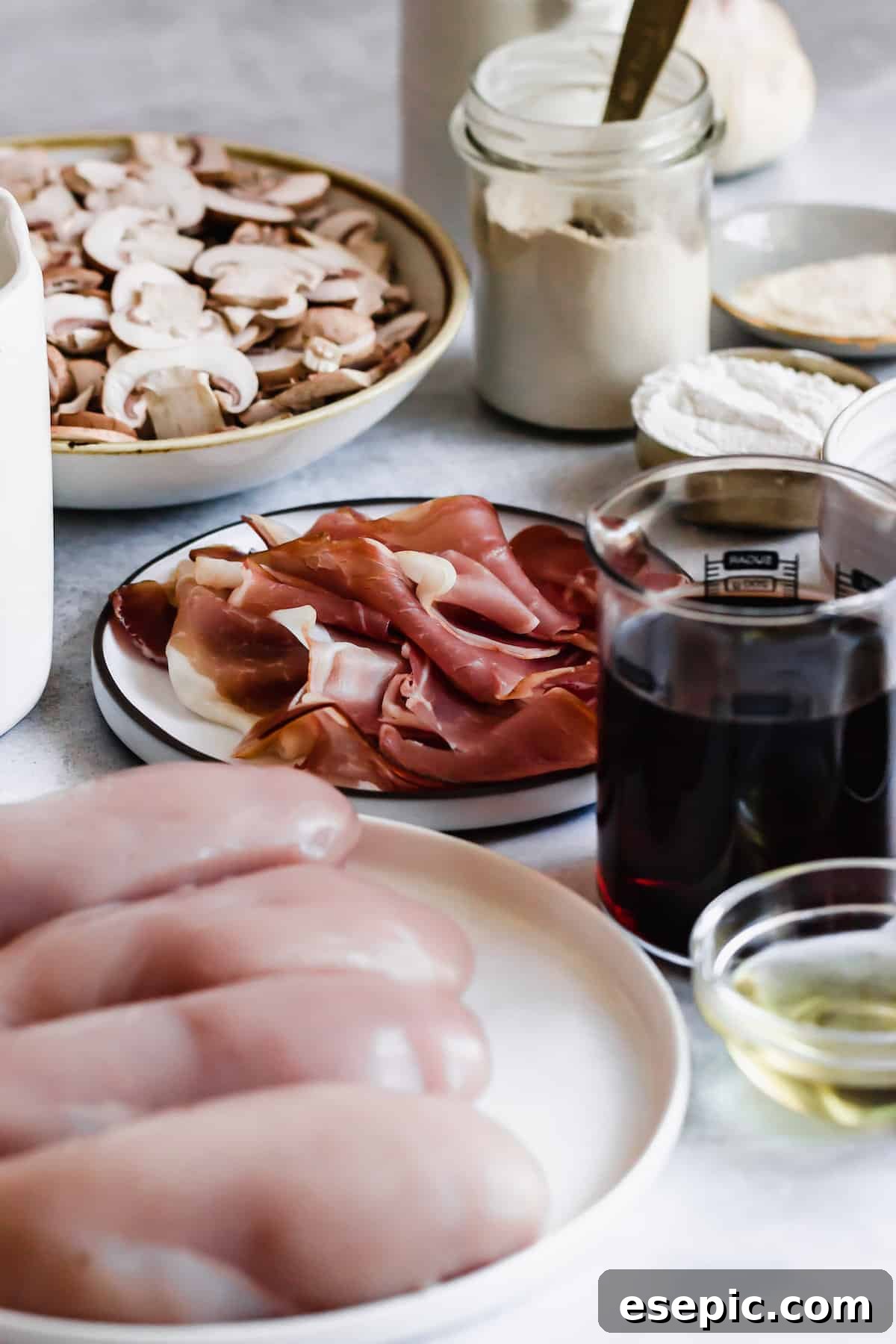 Luscious Marsala Chicken 4 Key ingredients for Chicken Marsala laid out: sliced white mushrooms, crispy prosciutto, all-purpose flour, and a glass of Marsala wine.