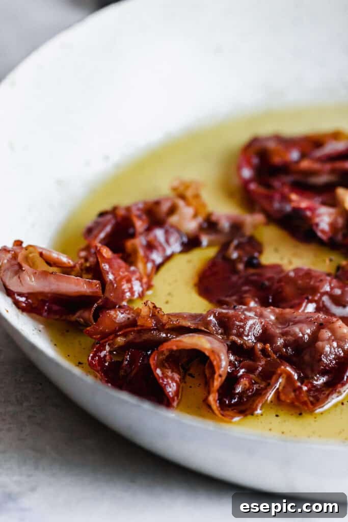 Proscuitto frying in oil in a saute pan.