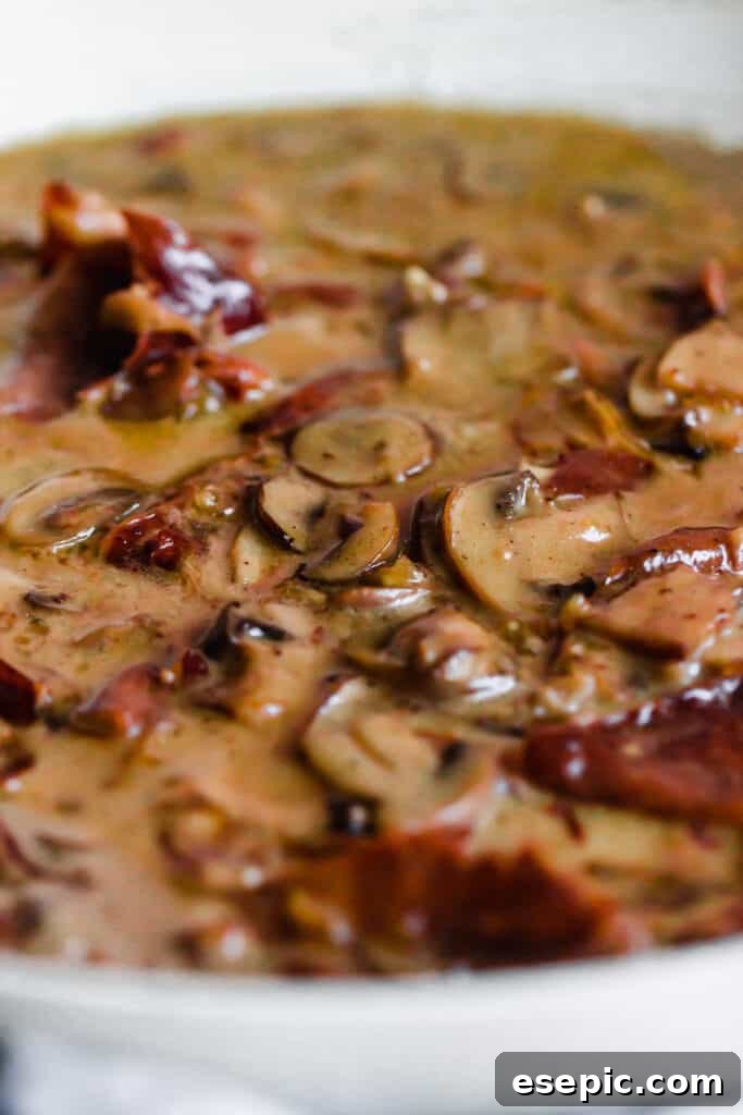 Mushrooms and proscuitto cooking in a creamy sauce.