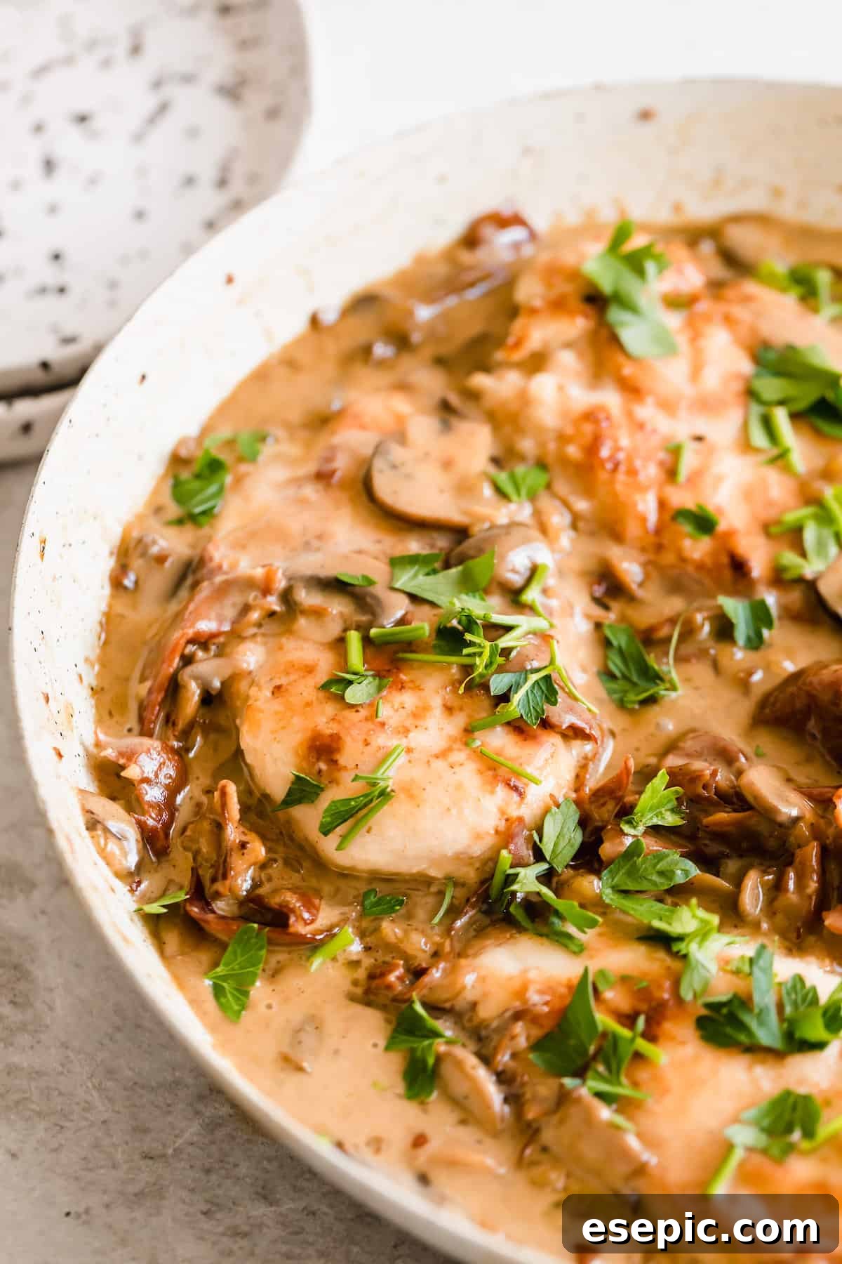Luscious Marsala Chicken 10 Creamy chicken marsala served in a white bowl, generously sprinkled with fresh herbs.
