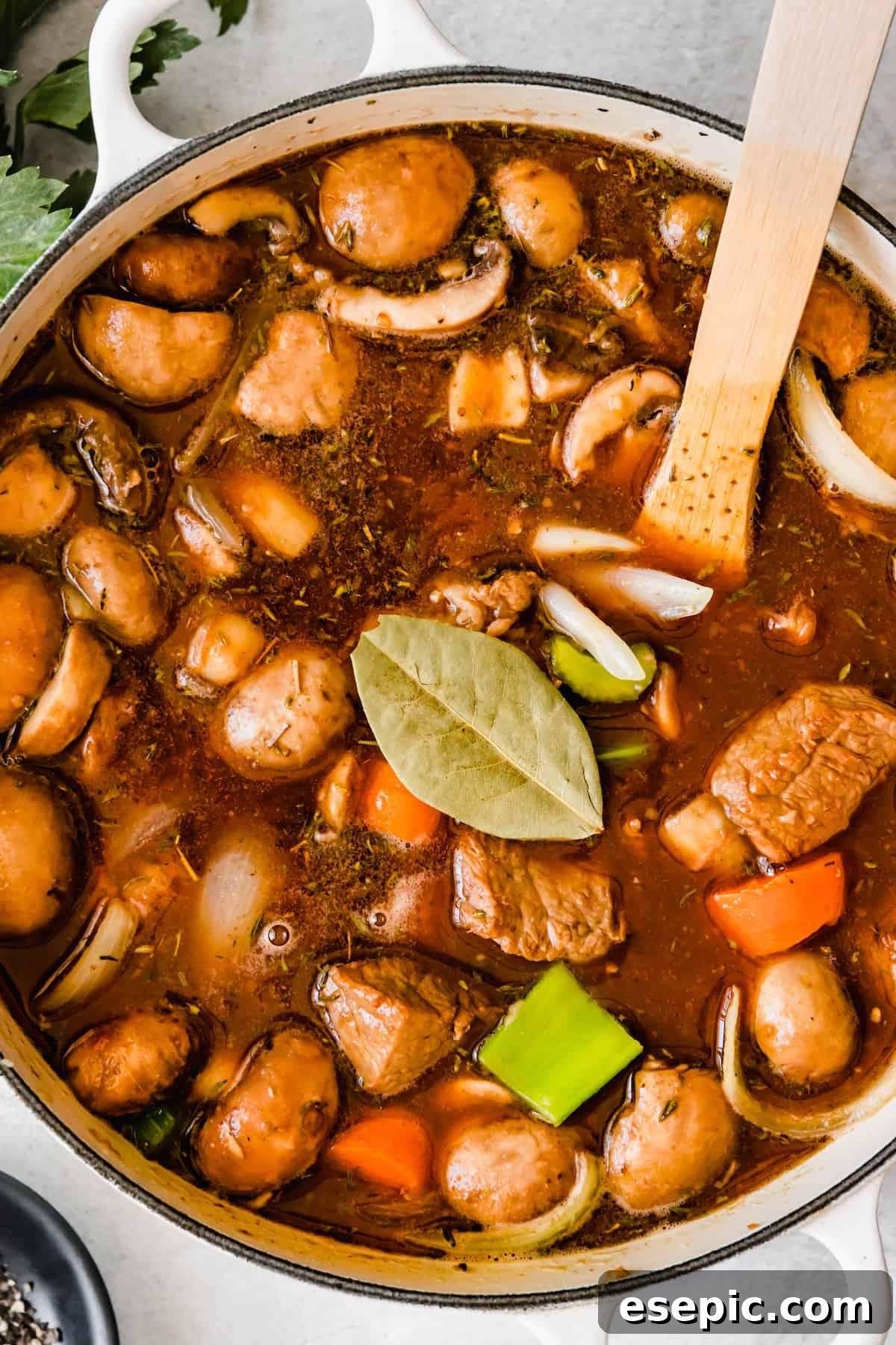 Slow-Simmered Guinness Beef Stew 12 A rich beef stew simmering gently in a pot, topped with a fresh bay leaf for aromatic infusion, highlighting the slow-cooking process.