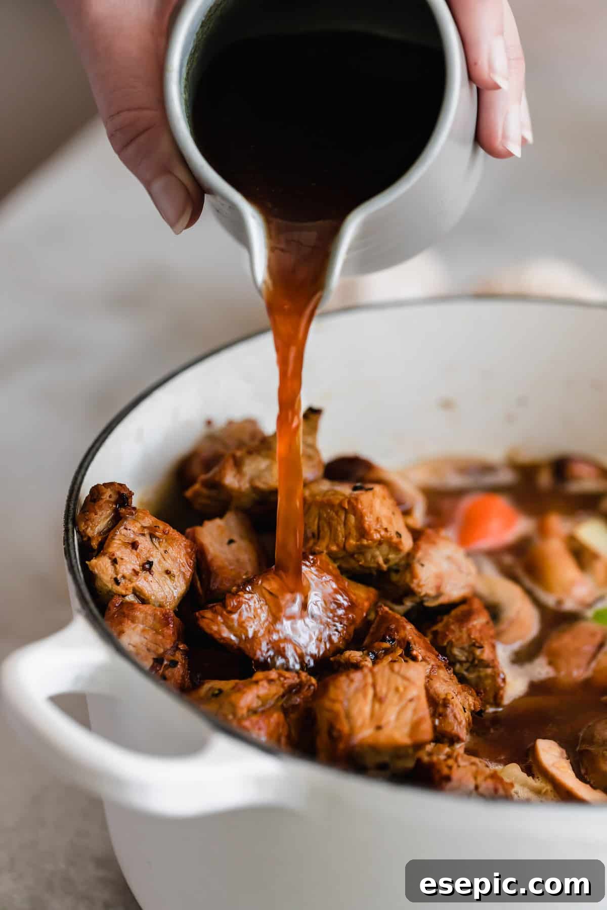 Slow-Simmered Guinness Beef Stew 5 Guinness beer being carefully poured into a pot of simmering beef stew, indicating a crucial step in preparing this rich, Irish-inspired dish.