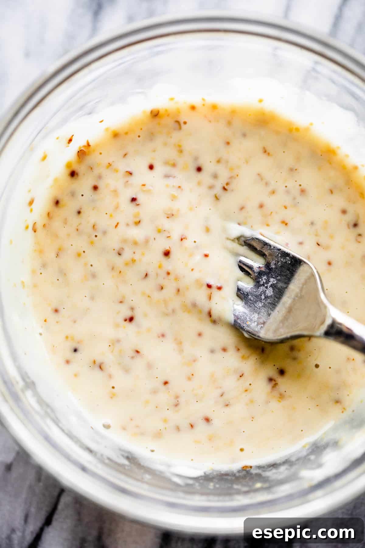 This baked Maple Mustard Salmon recipe is lightly seasoned, then brushed with a sweet and tangy sauce made from maple syrup and Dijon mustard! mixing maple mustard sauce in a clear glass bowl with a whisk