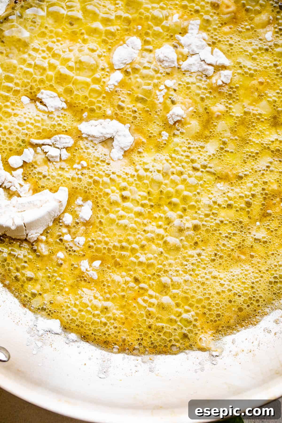 Cooking butter and flour together in a stainless steel skillet to create a roux for the creamy spinach sauce.