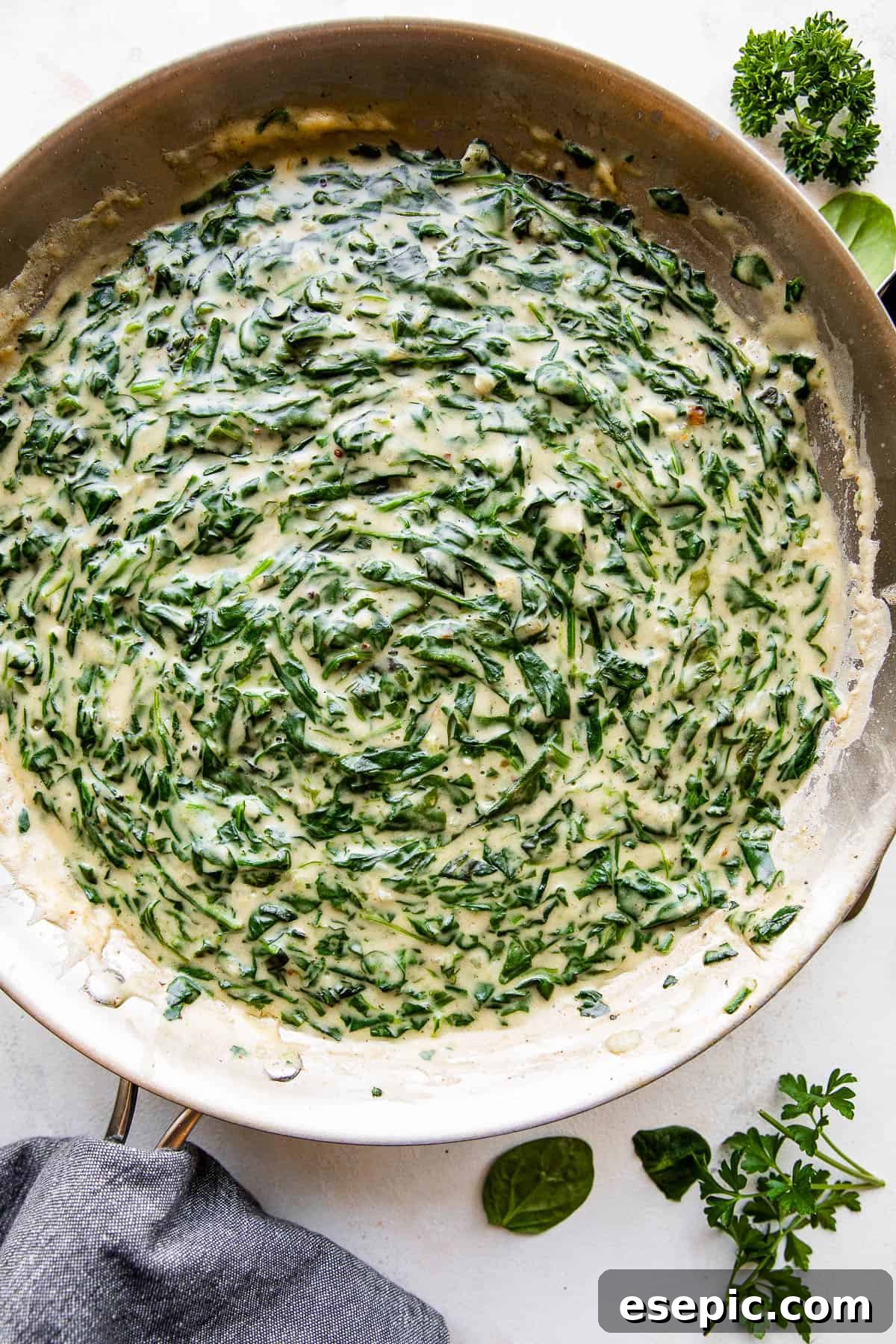 Close-up overhead view of the finished steakhouse creamed spinach cooking in a large skillet, showcasing its rich, creamy texture and vibrant green color.