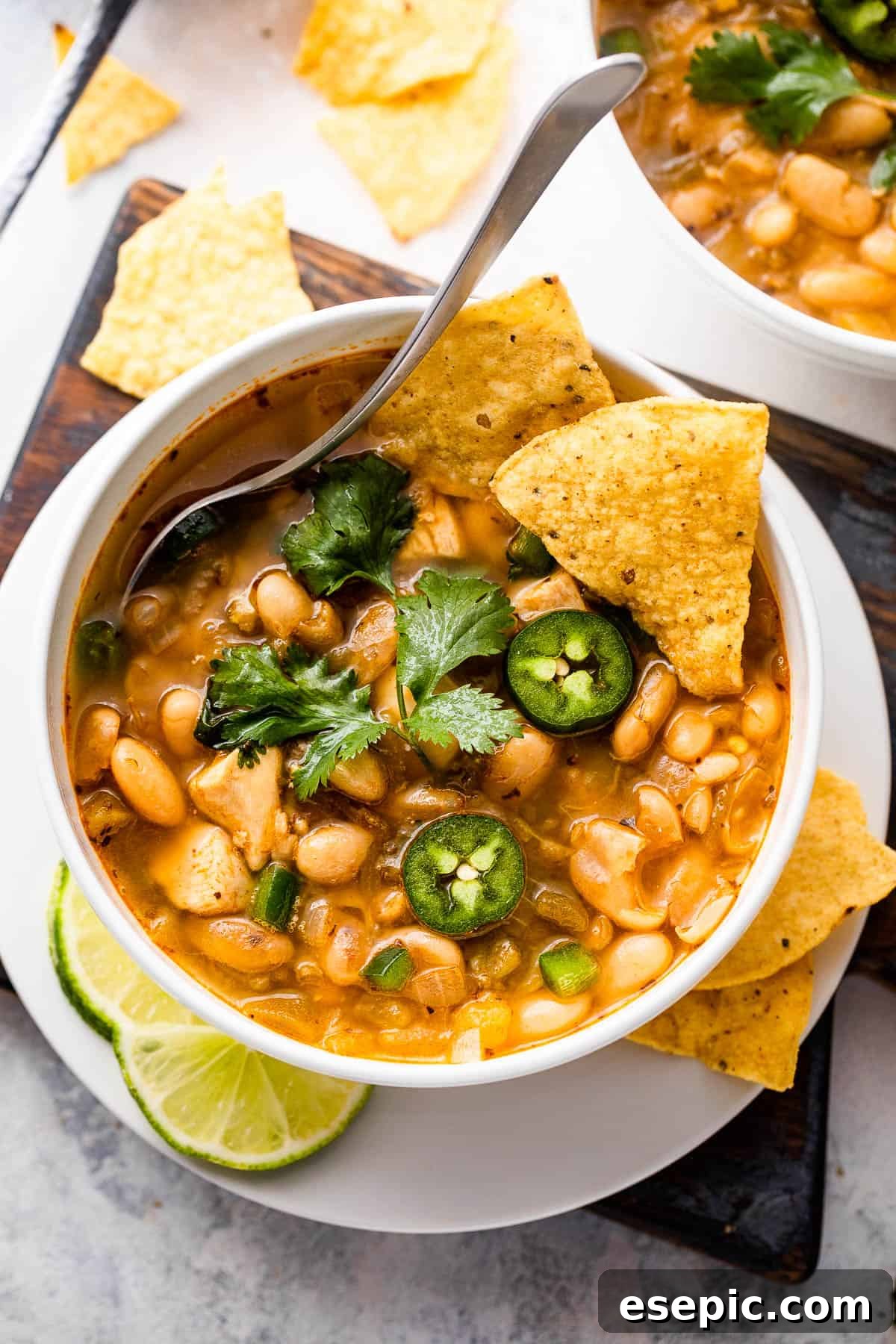overhead shot of white soup bowls with chicken chili, garnished with cilantro and lime