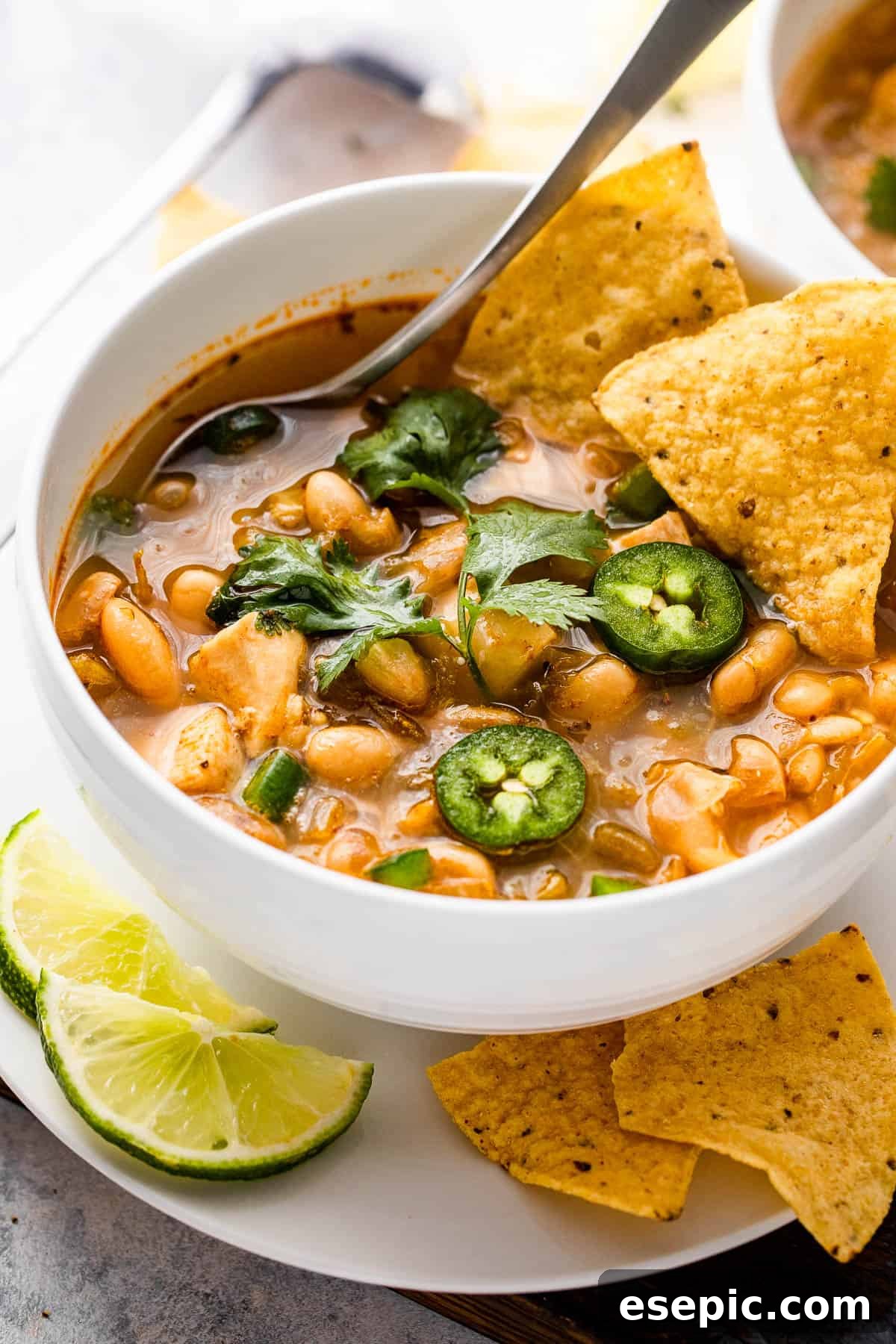 Hearty Chicken Chili 3 side shot of a chicken chili in a bowl topped with jalapenos and tortilla chips