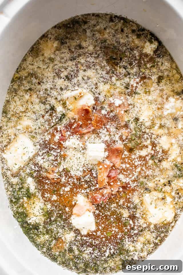 chicken broth, cubed cream cheese, bacon, chicken breasts, and seasonings inside the insert of a slow cooker