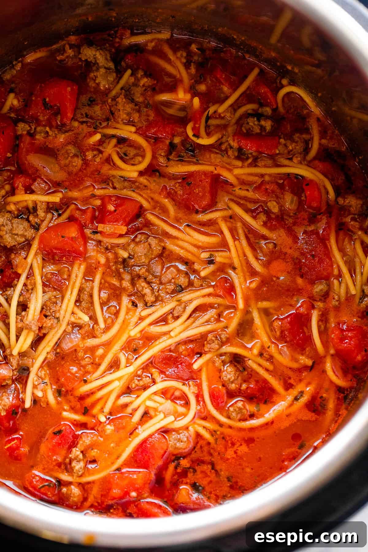 Close up view of spaghetti cooking in the Instant Pot with sauce and noodles visible.