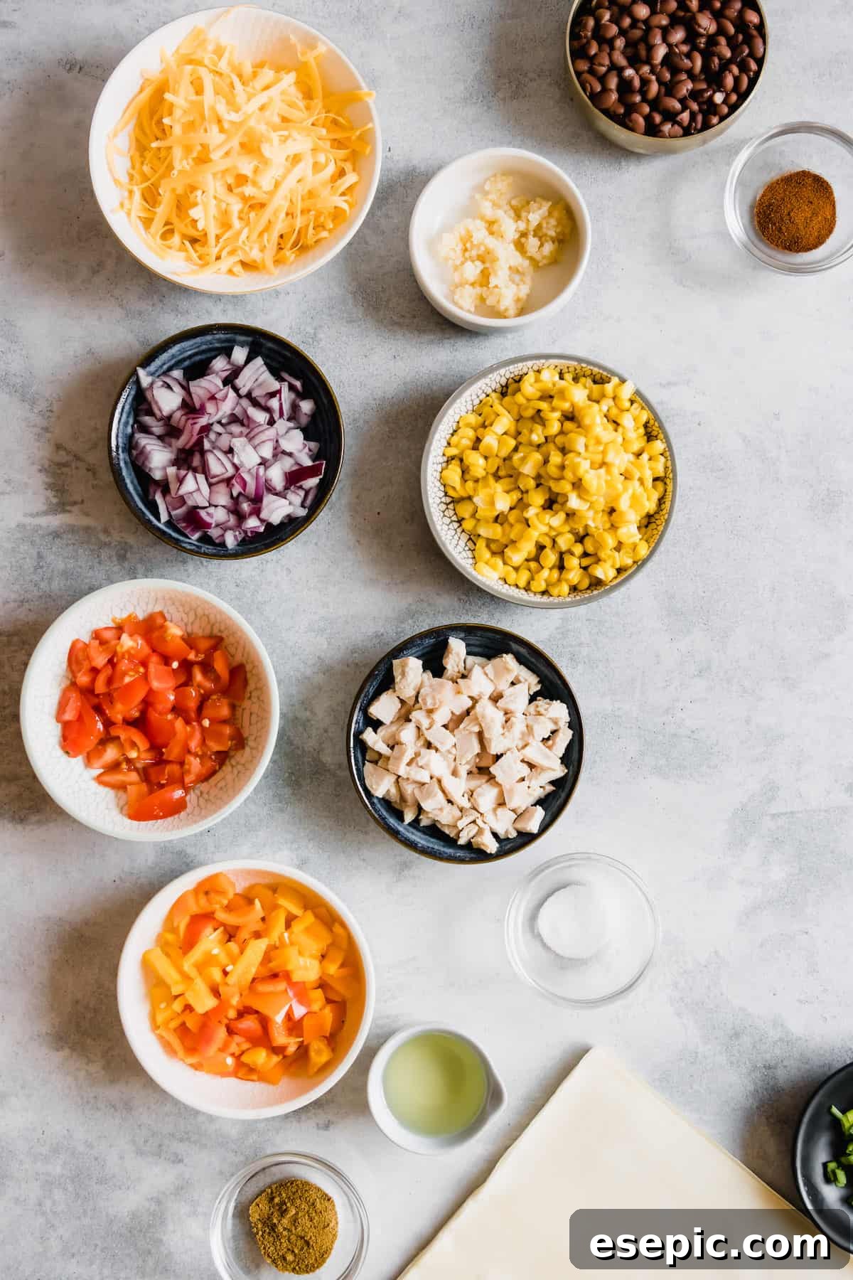 Shredded Cheese, Diced Tomatoes, Diced Chicken and the Rest of the Egg Roll Ingredients on a Countertop
