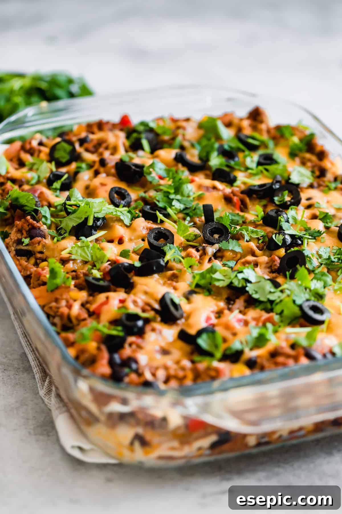 A Taco Casserole in a Glass Pan on Top of a White and Tan Dish Towel