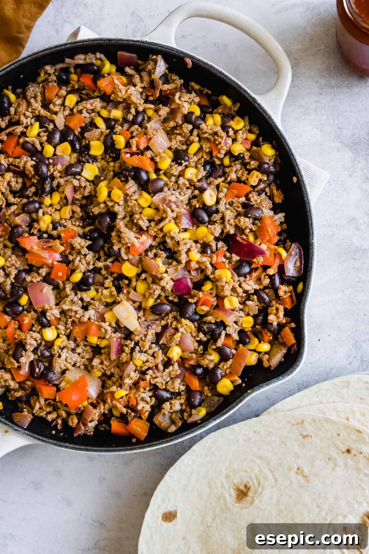 A Pan Filled with Mexican Lasagna Filling Beside Three Soft Tortillas