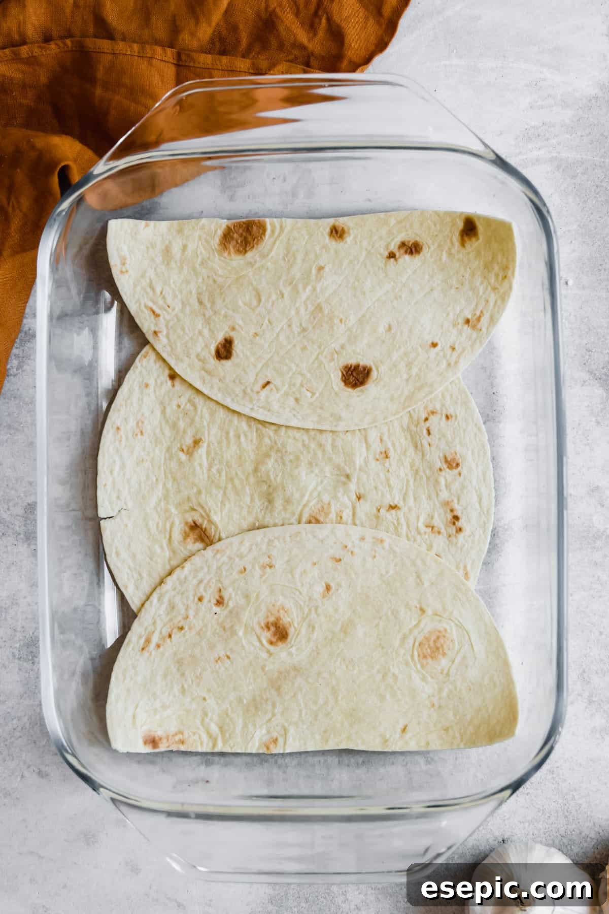 A Layer of Soft Corn Tortillas in a Glass Baking Dish