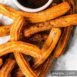 Homemade churros served on a plate with a bowl of chocolate sauce, a delicious and easy dessert recipe.