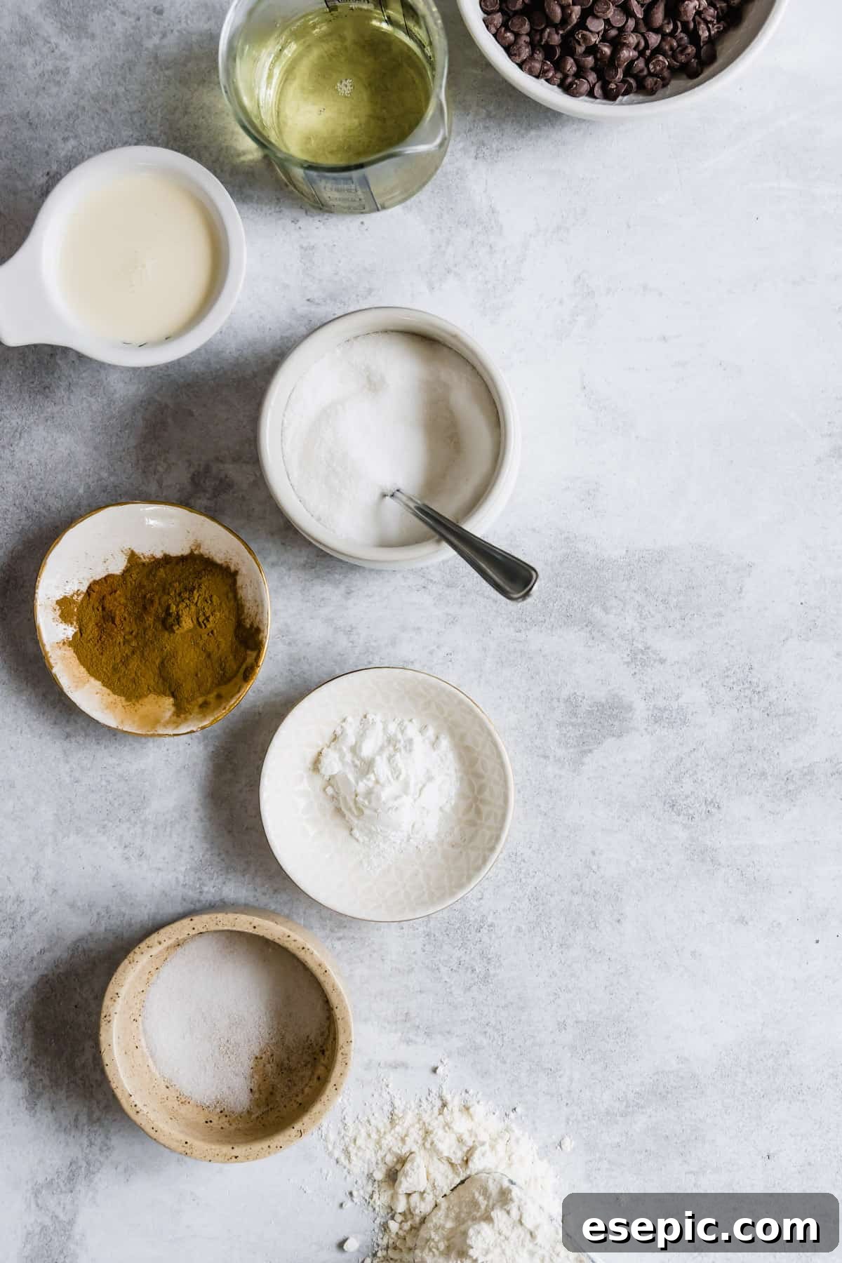 A vibrant flat lay of all the essential ingredients for making homemade churros and chocolate dipping sauce, including chocolate chips, salt, sugar, and cinnamon, neatly arranged on a rustic wooden surface.