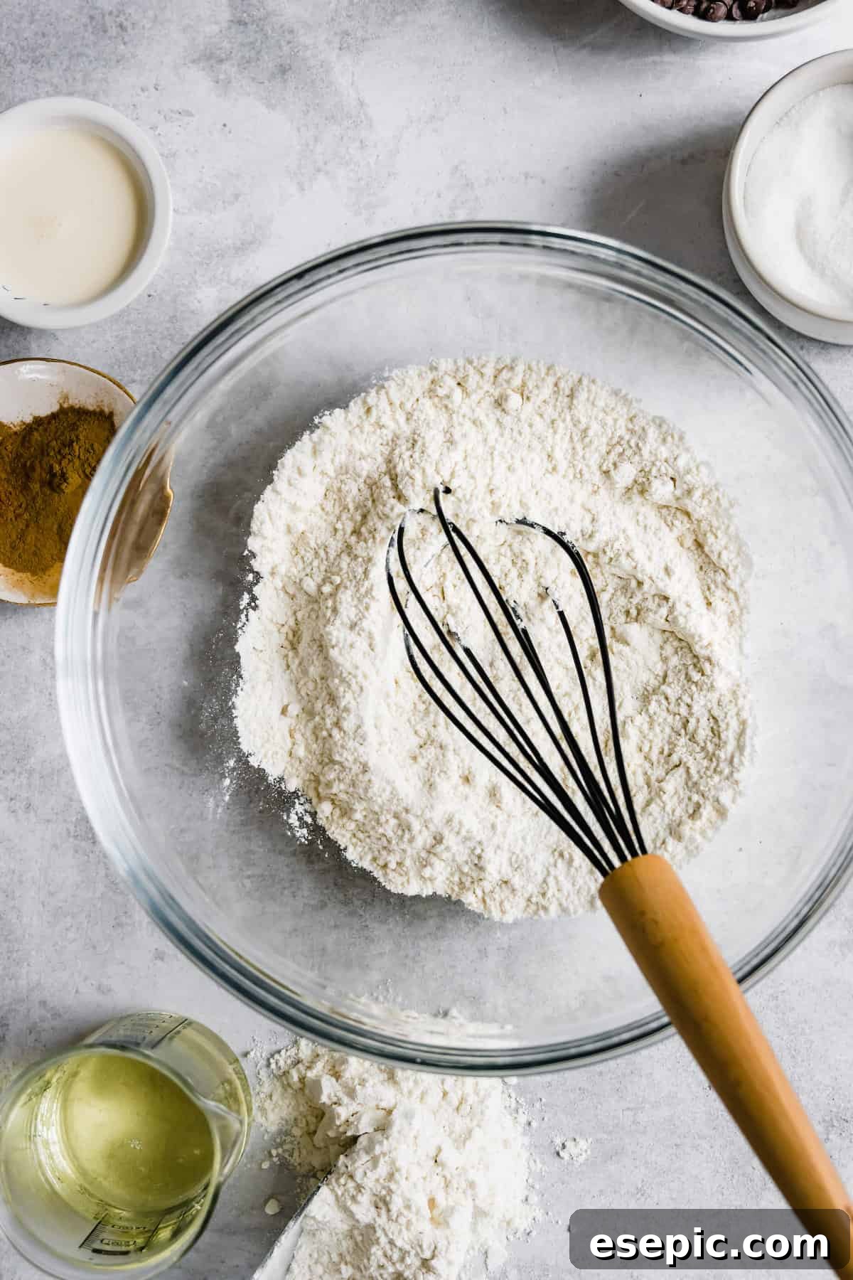 A clear glass bowl filled with the pre-mixed dry ingredients for homemade churros: flour, baking powder, and salt, ready for the wet ingredients to be added.
