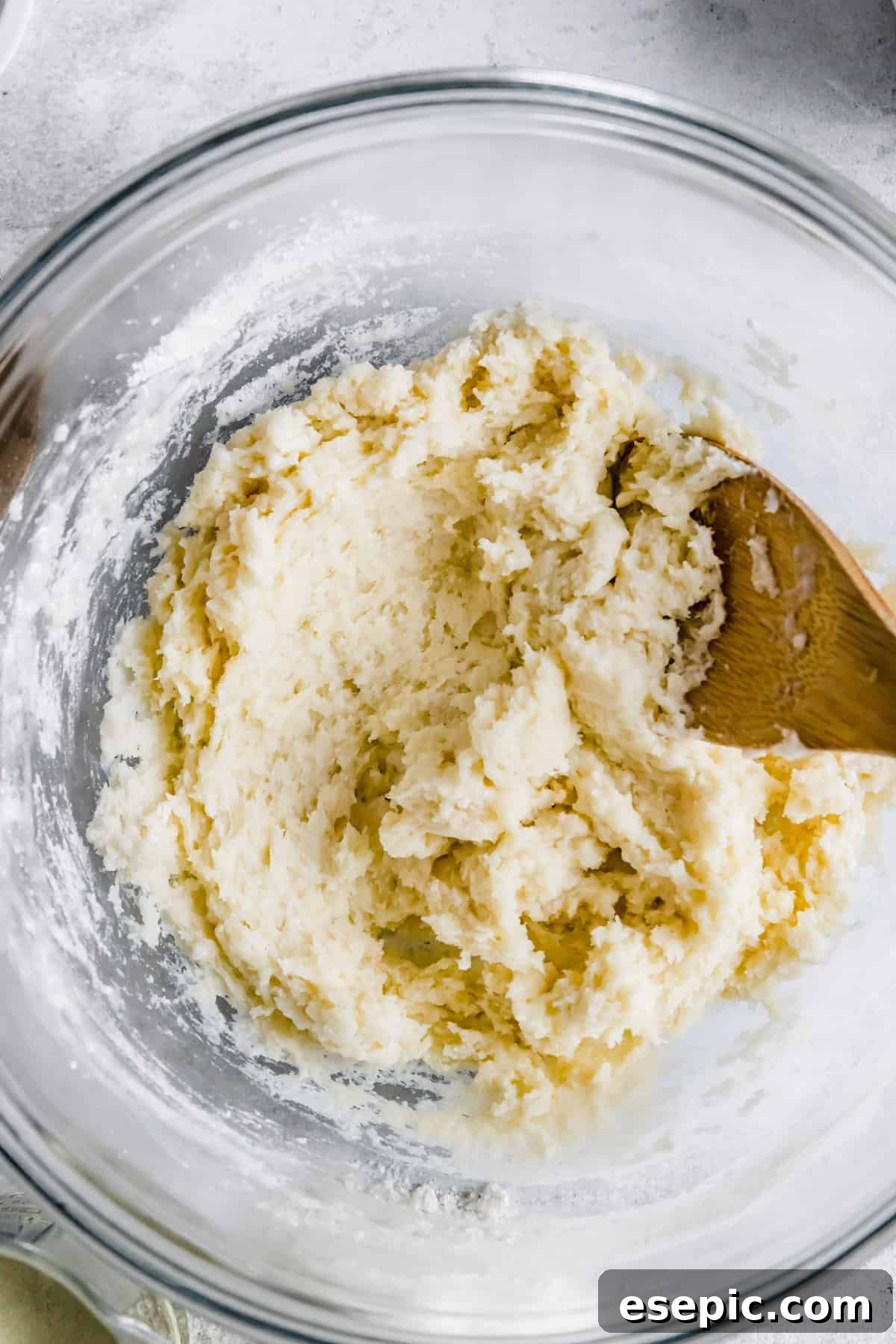A large glass mixing bowl containing freshly prepared churro dough, thick and sticky, ready for piping and frying.
