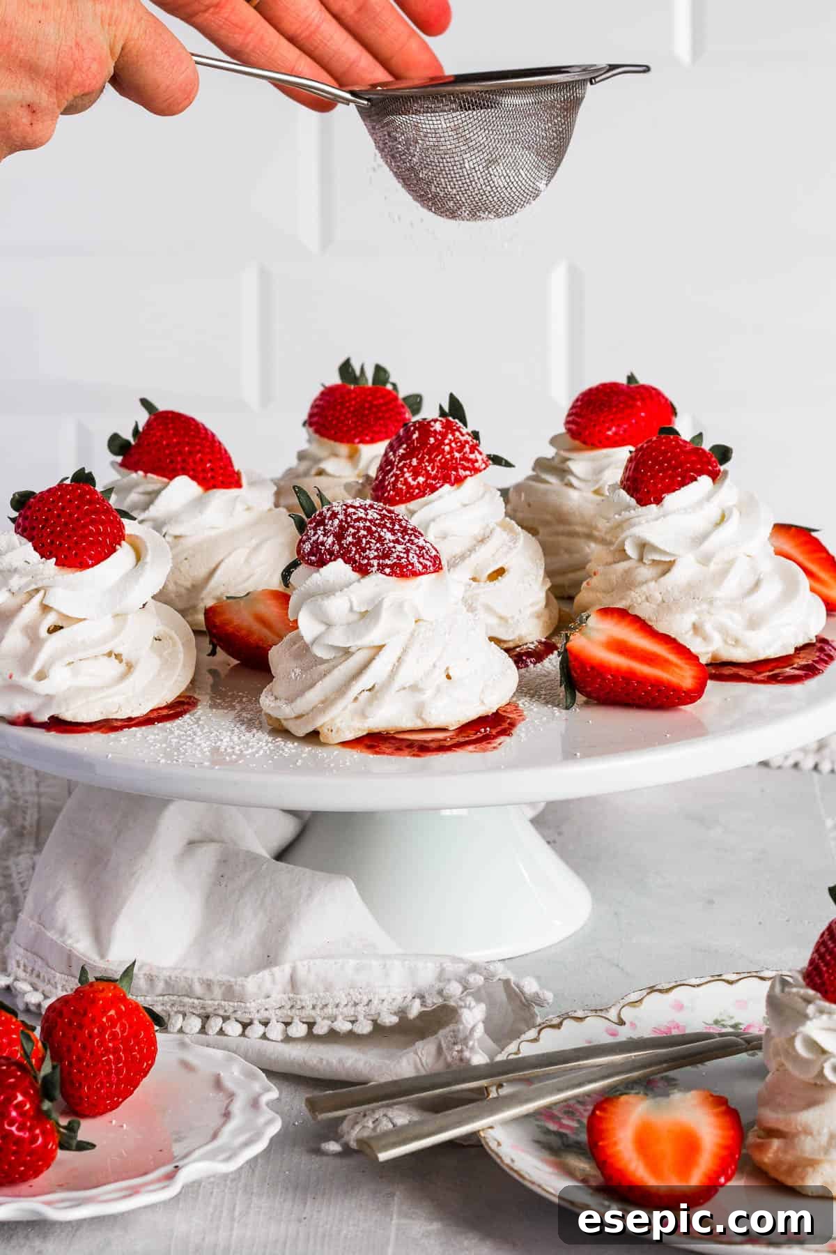 Effortless Strawberry Meringue Nests 12 A dusting of confectioners' sugar being sifted over finished pavlovas, adding a beautiful final touch.