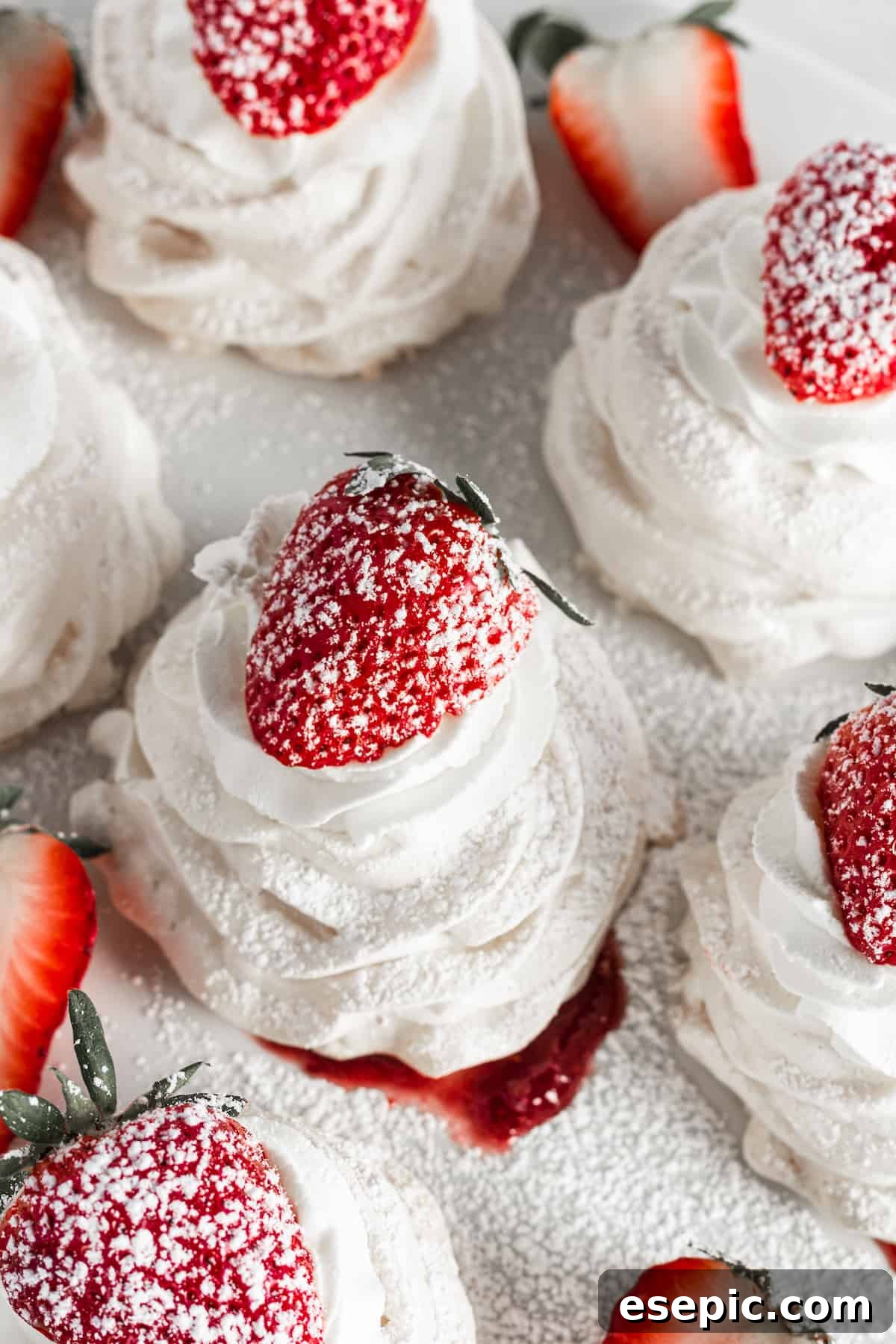 Effortless Strawberry Meringue Nests 14 A collection of Strawberry Pavlova Nests, garnished with fresh strawberries and a delicate dusting of powdered sugar, ready to be enjoyed.