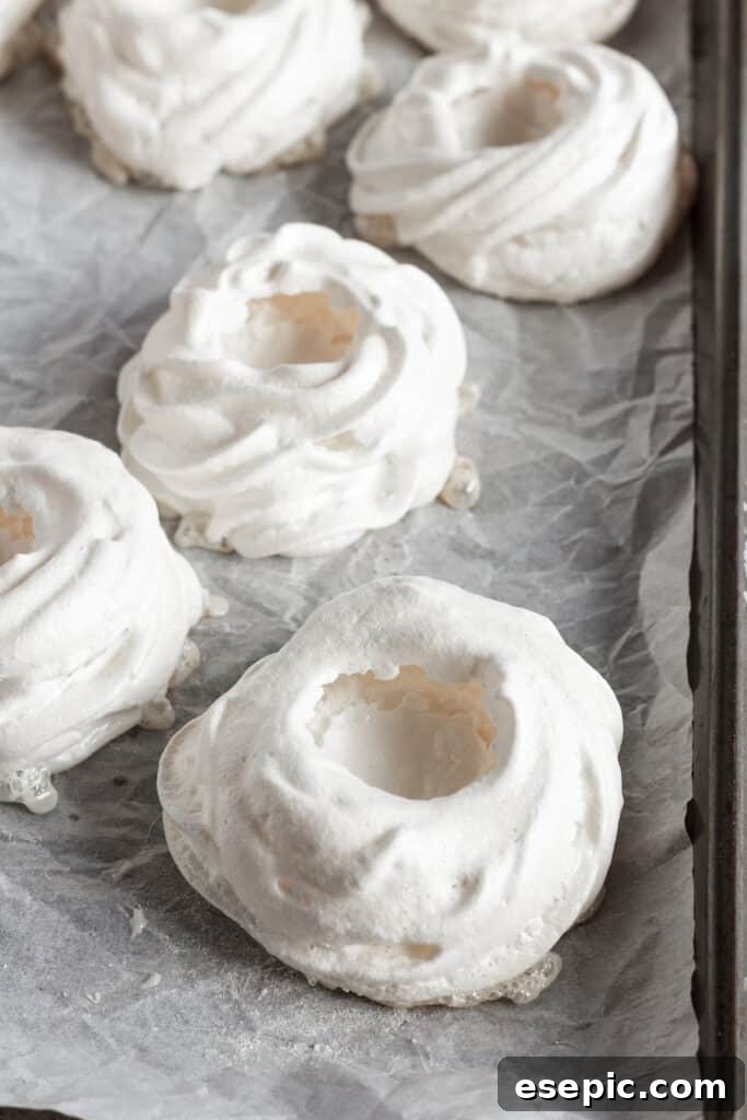 Effortless Strawberry Meringue Nests 9 Rows of perfectly shaped pavlova nests resting on a baking sheet, ready for baking.