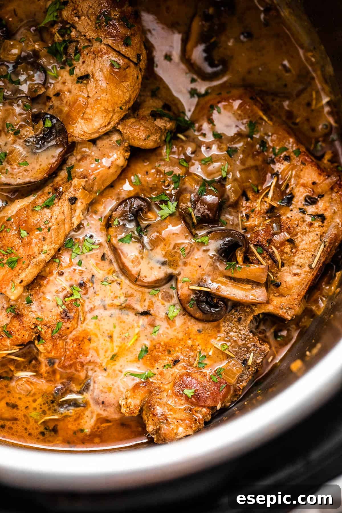 Close-up shot of perfectly cooked pork chops in the Instant Pot, generously topped with creamy mushroom gravy