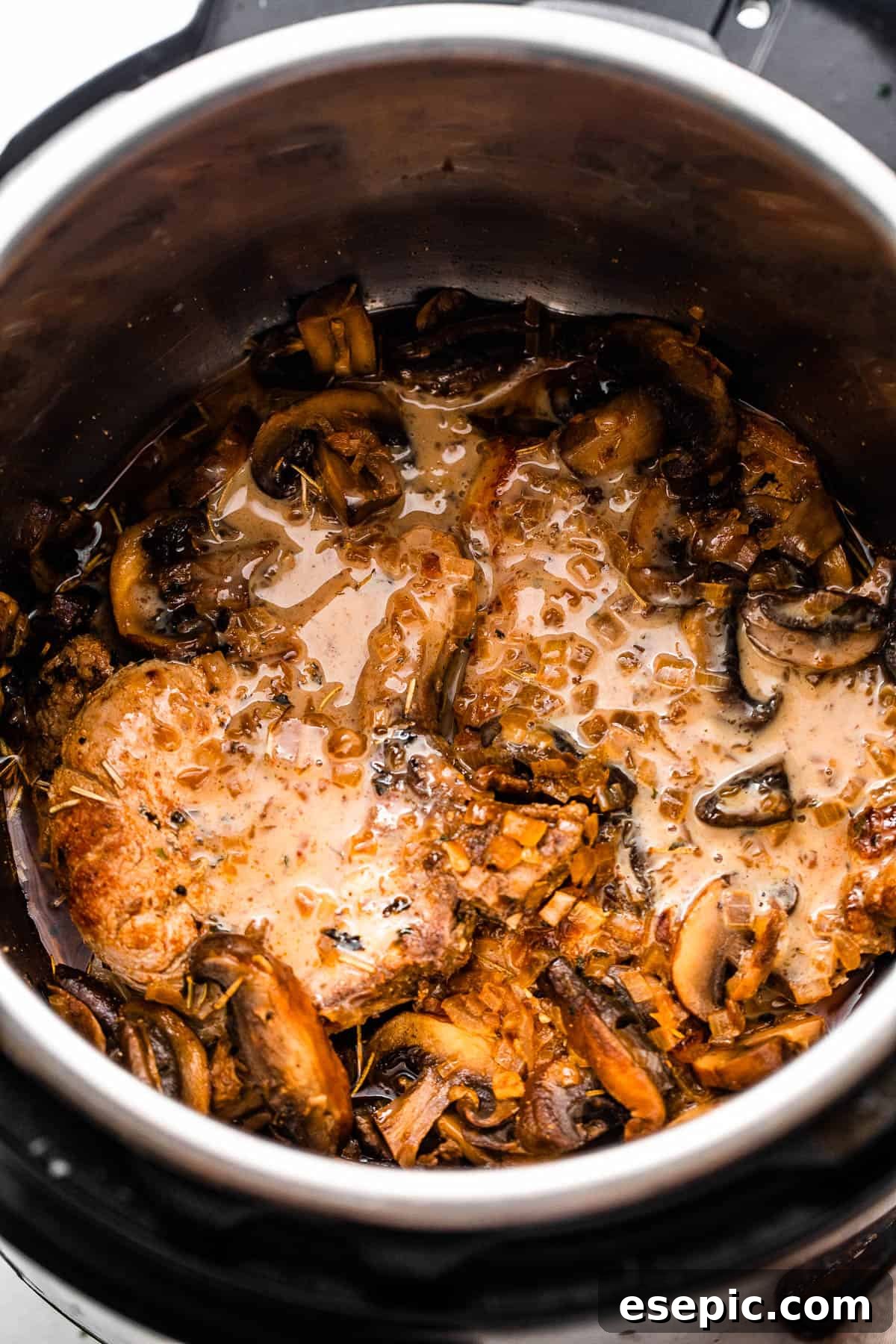Overhead shot of two pork chops in the Instant Pot, covered with creamy mushroom gravy