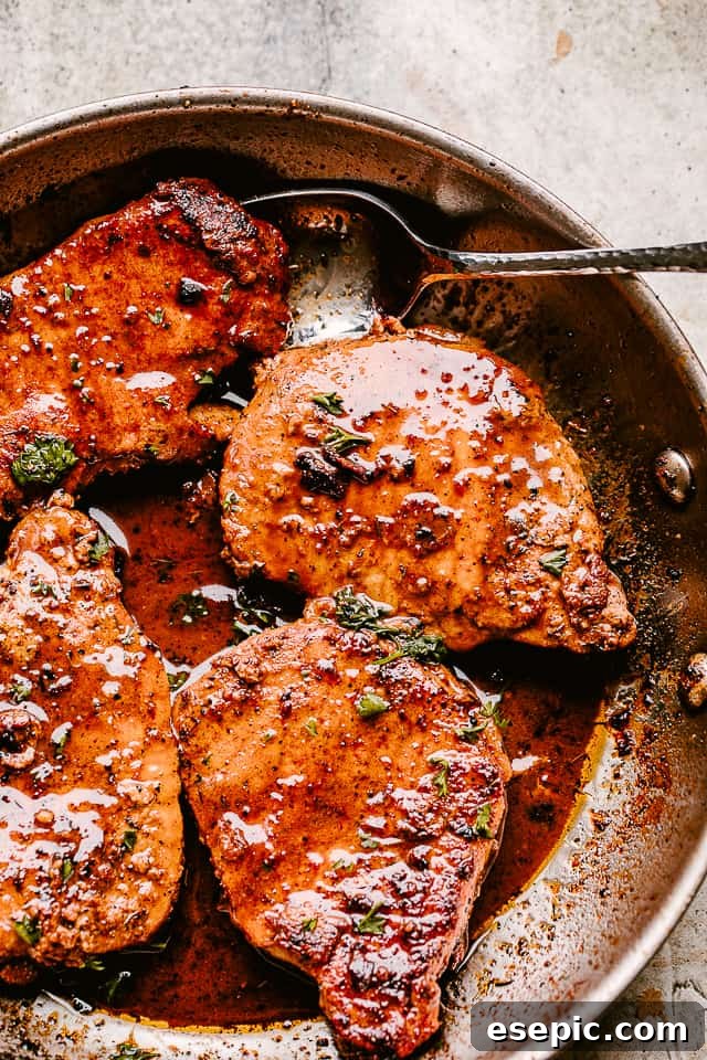 Skillet with golden brown garlic parmesan pan-fried pork chops, coated in a luscious sauce