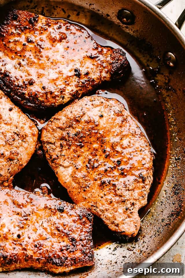 Pork chops searing in a hot skillet with olive oil and butter