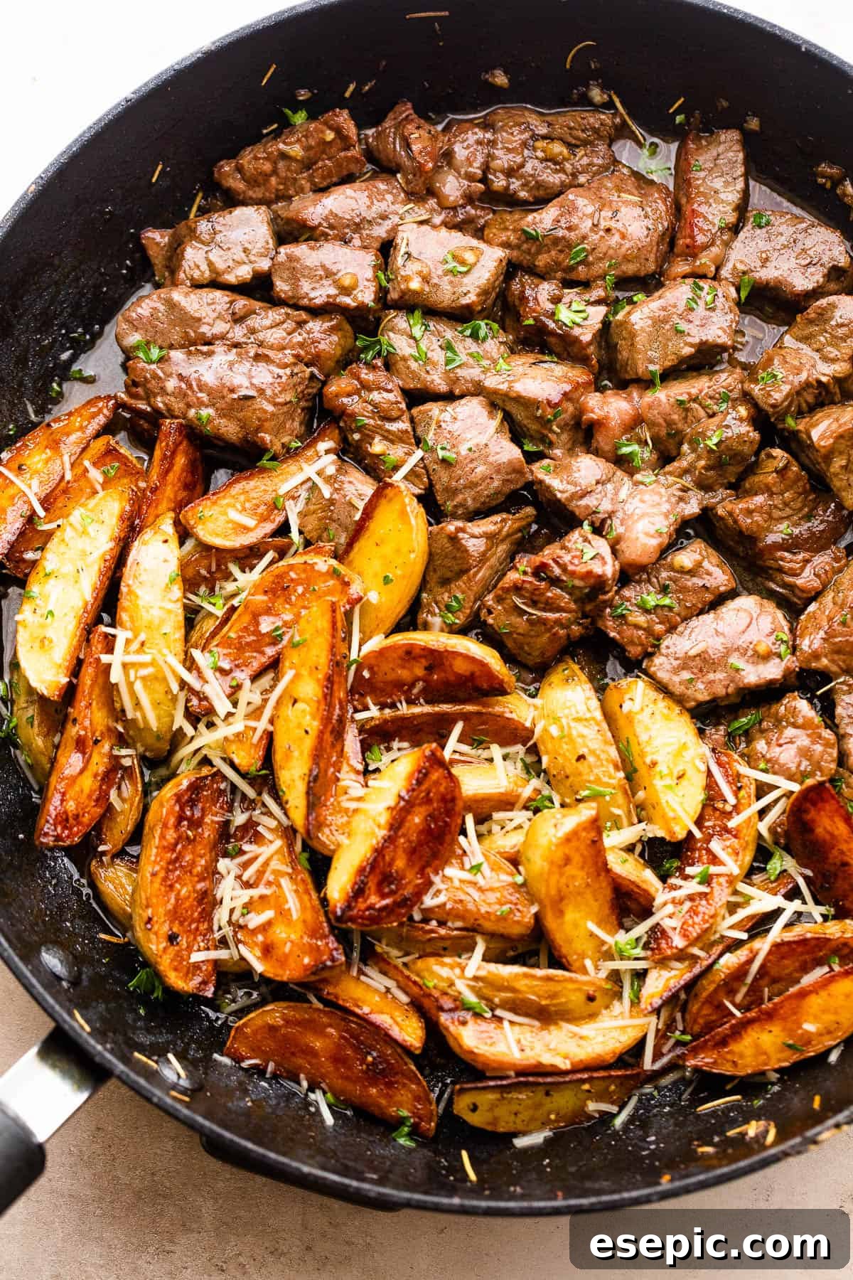 Garlicky Steak Bites and Crispy Potatoes 2 cubed steak and quartered potatoes cooking in a skillet