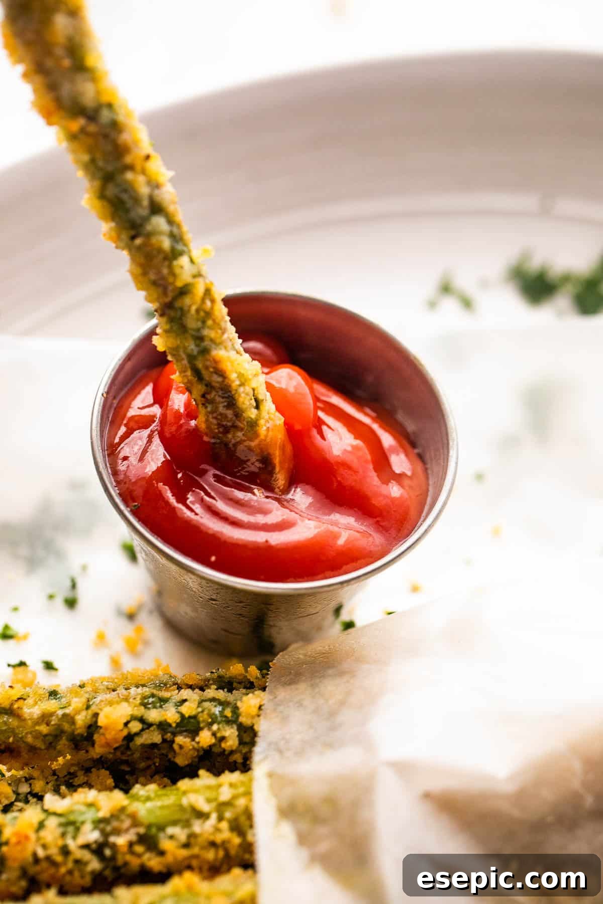 Crispy Parmesan Panko Asparagus Sticks 3 dipping asparagus fries in ketchup