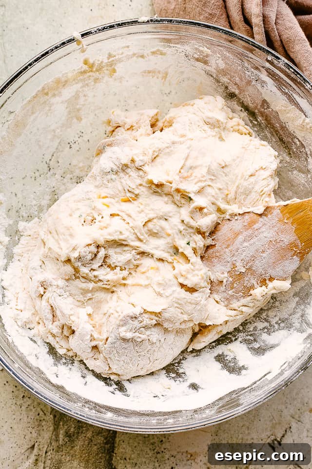 Making warm and crusty homemade bread is easier than you’ve imagined with this no knead cheese bread recipe. Cheesy, crusty, and oh-so-good! No-knead cheese bread dough resting and rising in a cast iron skillet.