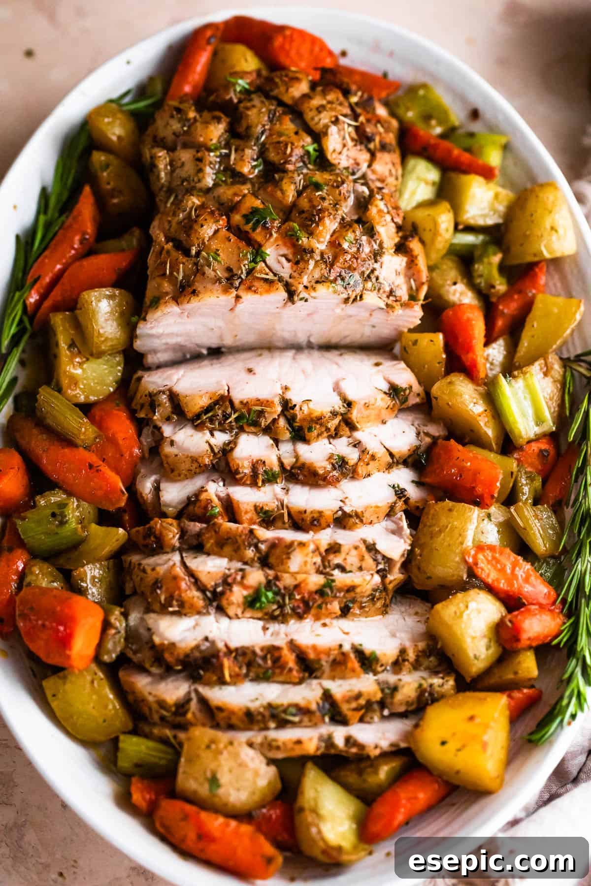 Garlic Herb Pork Loin with Roasted Root Vegetables 3 Overhead shot of an oval plate with cooked and sliced pork loin roast and roasted vegetables, showcasing the vibrant colors and appealing presentation.