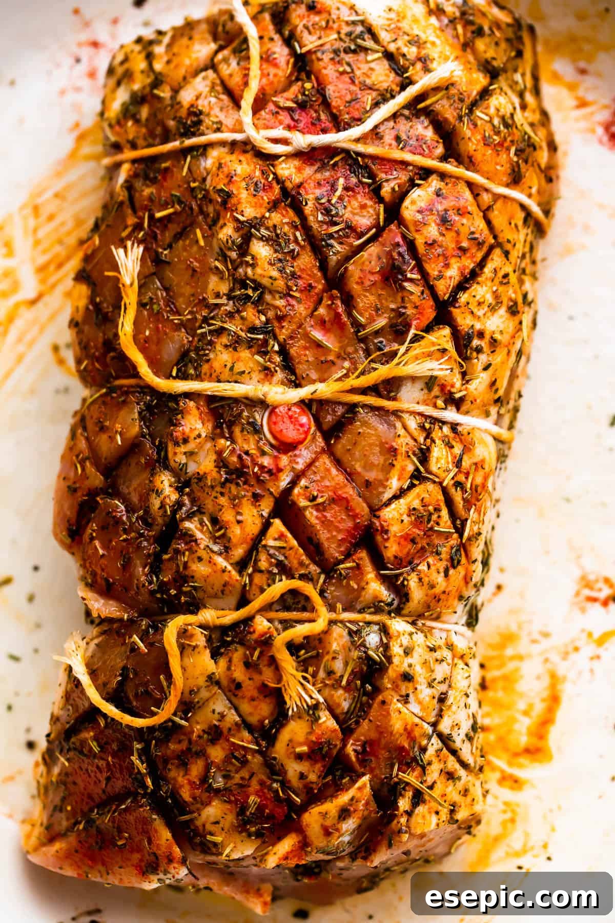 Garlic Herb Pork Loin with Roasted Root Vegetables 4 Close-up of a raw pork loin roast, meticulously tied with kitchen twine, ready for seasoning and preparation.