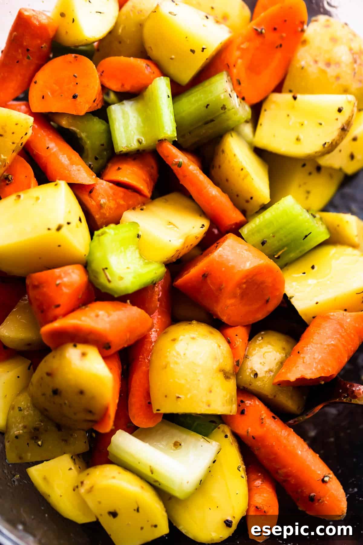 Garlic Herb Pork Loin with Roasted Root Vegetables 5 Glass bowl filled with chopped pieces of fresh carrots, celery, and potatoes, prepped and ready for roasting.