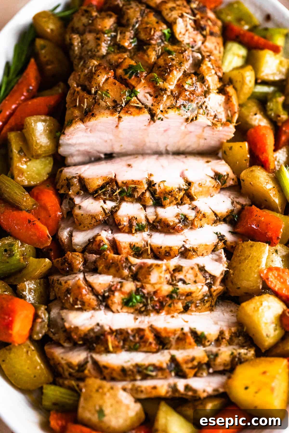 Garlic Herb Pork Loin with Roasted Root Vegetables 8 Overhead shot of an oval plate with cooked and sliced pork loin roast and roasted vegetables arranged around the roast, ready for a delicious dinner.