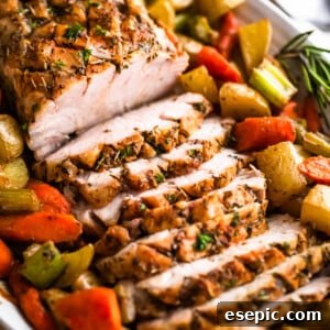 A perfectly cooked and sliced pork loin roast, surrounded by vibrant roasted vegetables, presented on a plate.