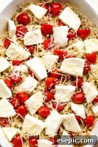 Flavorful Caprese Chicken Bake 9 chicken caprese casserole in a white baking dish topped with fresh mozzarella chunks and cherry tomatoes