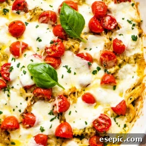 Caprese Chicken Casserole in a white baking dish topped with basil leaves and cherry tomatoes