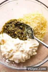 mixing together basil pesto, mayonnaise, and parmesan cheese
