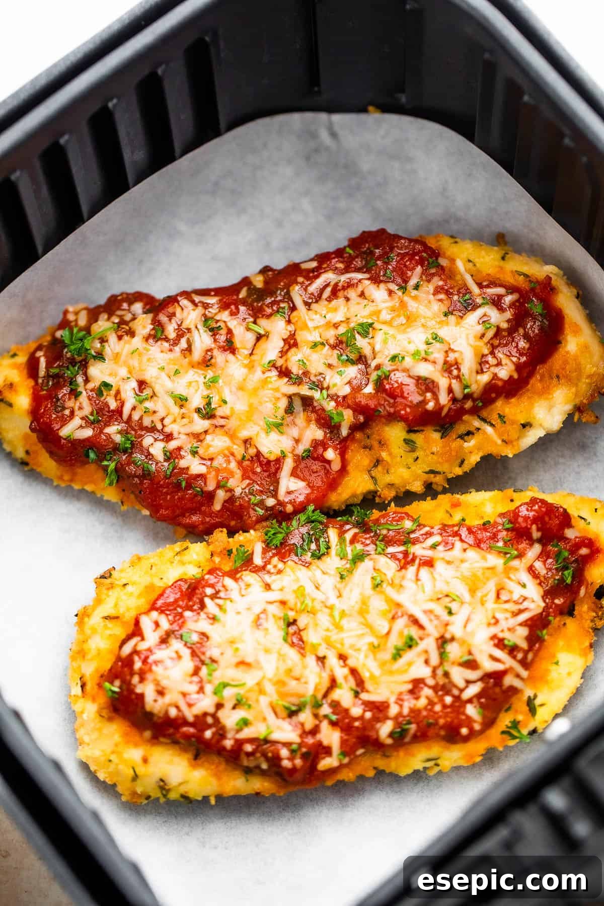 Crispy Air Fryer Chicken Parm 2 Two breaded chicken cutlets ready for the air fryer, topped with marinara sauce and shredded Parmesan cheese for Air Fryer Chicken Parmesan