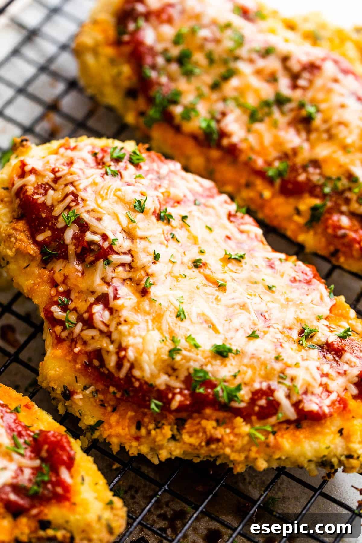 Crispy Air Fryer Chicken Parm 3 A close-up of a perfectly cooked Air Fryer Chicken Parmesan cutlet resting on a wire rack, showcasing its golden crust and melted cheese.