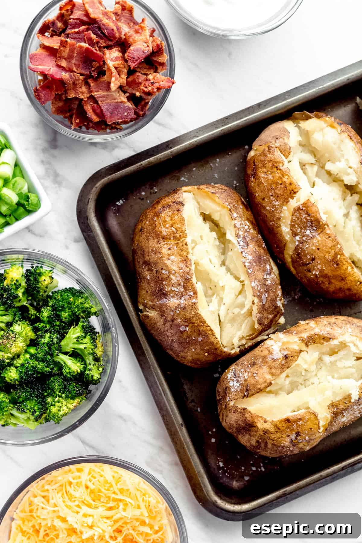 Three Instant Pot Baked Potatoes Beside Bowls of Cheese, Broccoli, Bacon, Chopped Green Onions and Sour Cream