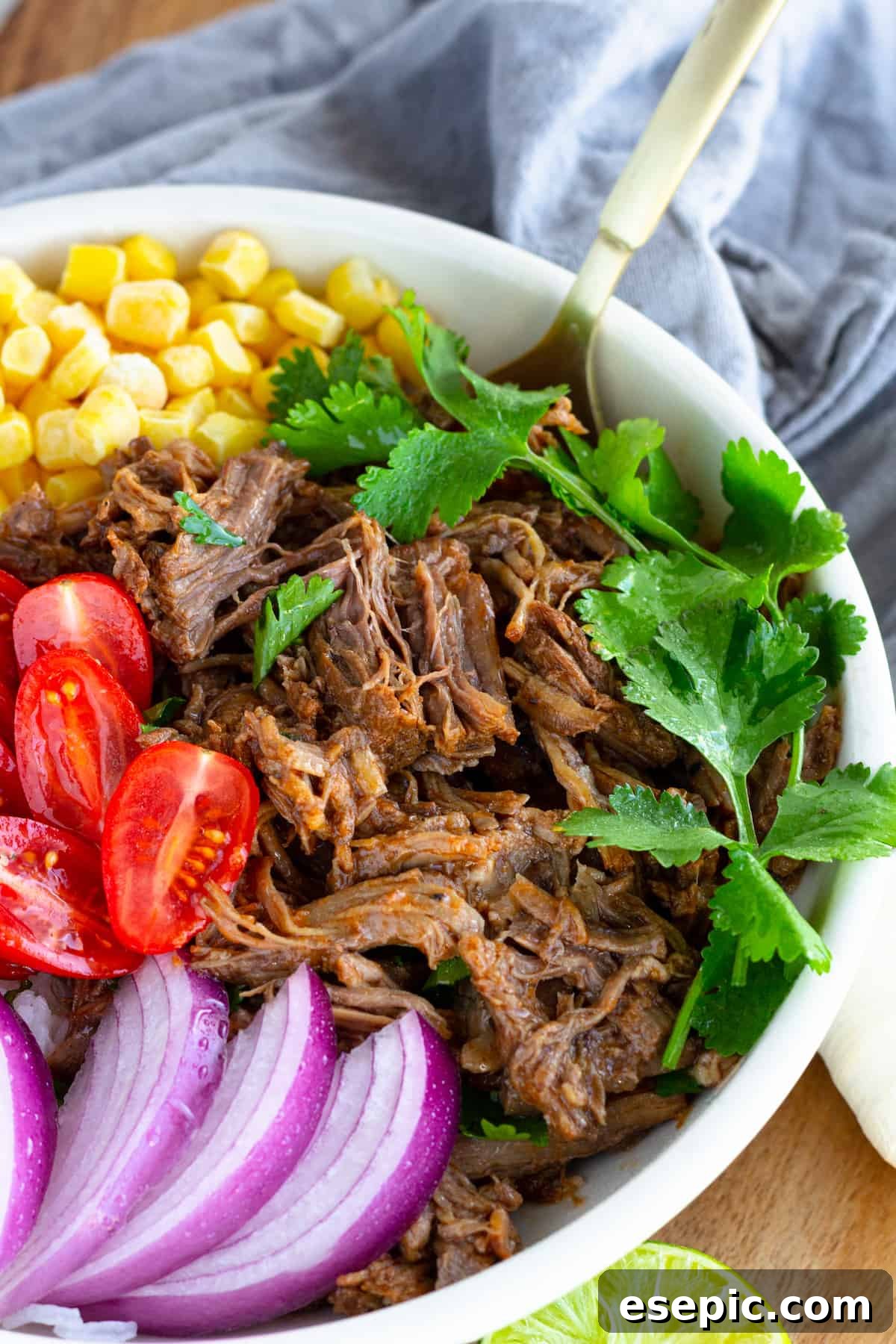 A Beef Barbacoa Burrito Bowl with a Parsley Garnish and a Golden Spoon Inside