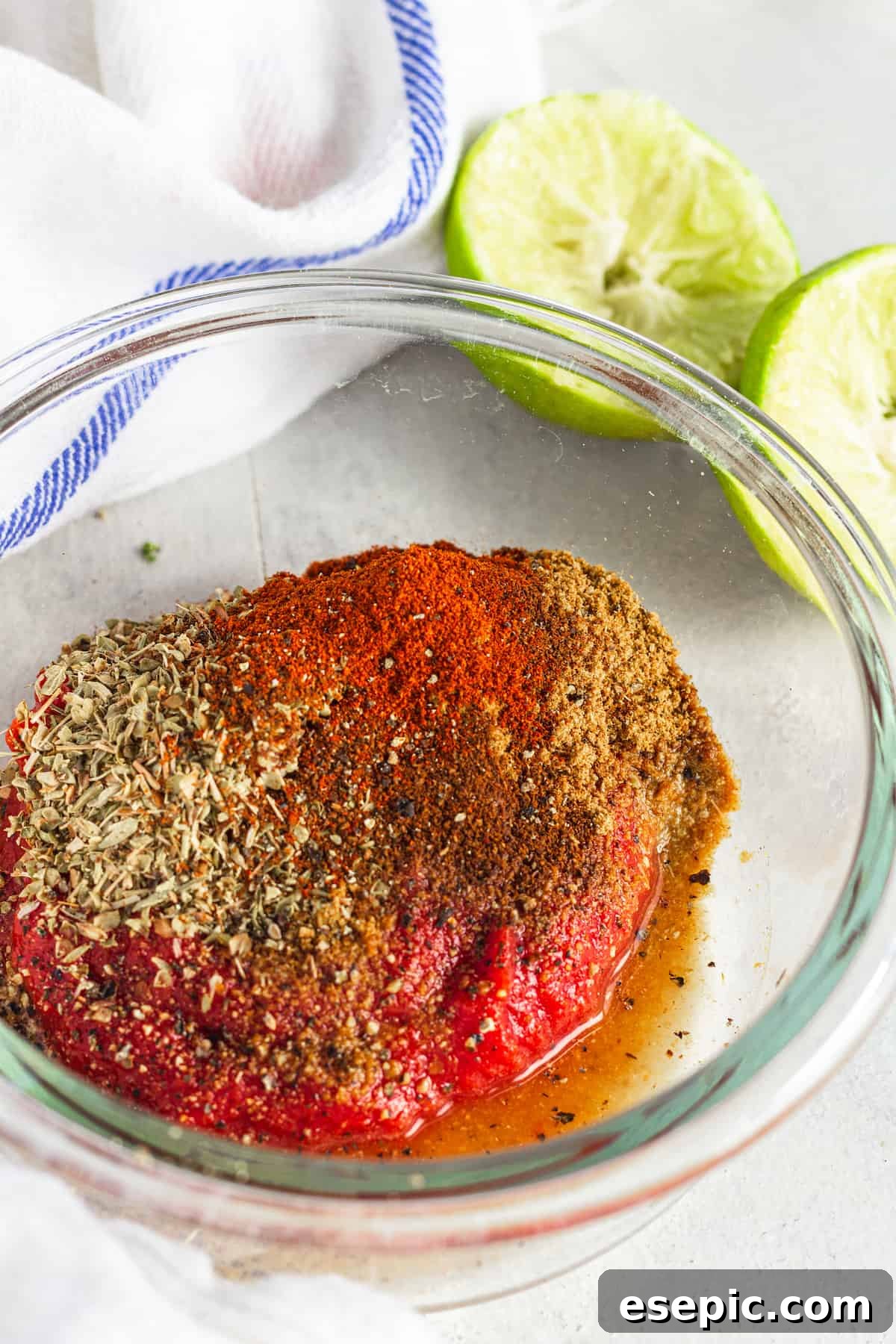 The Tomato Paste, Seasoning and Lime Juice Mixture in a Glass Bowl Beside a Juiced Lime