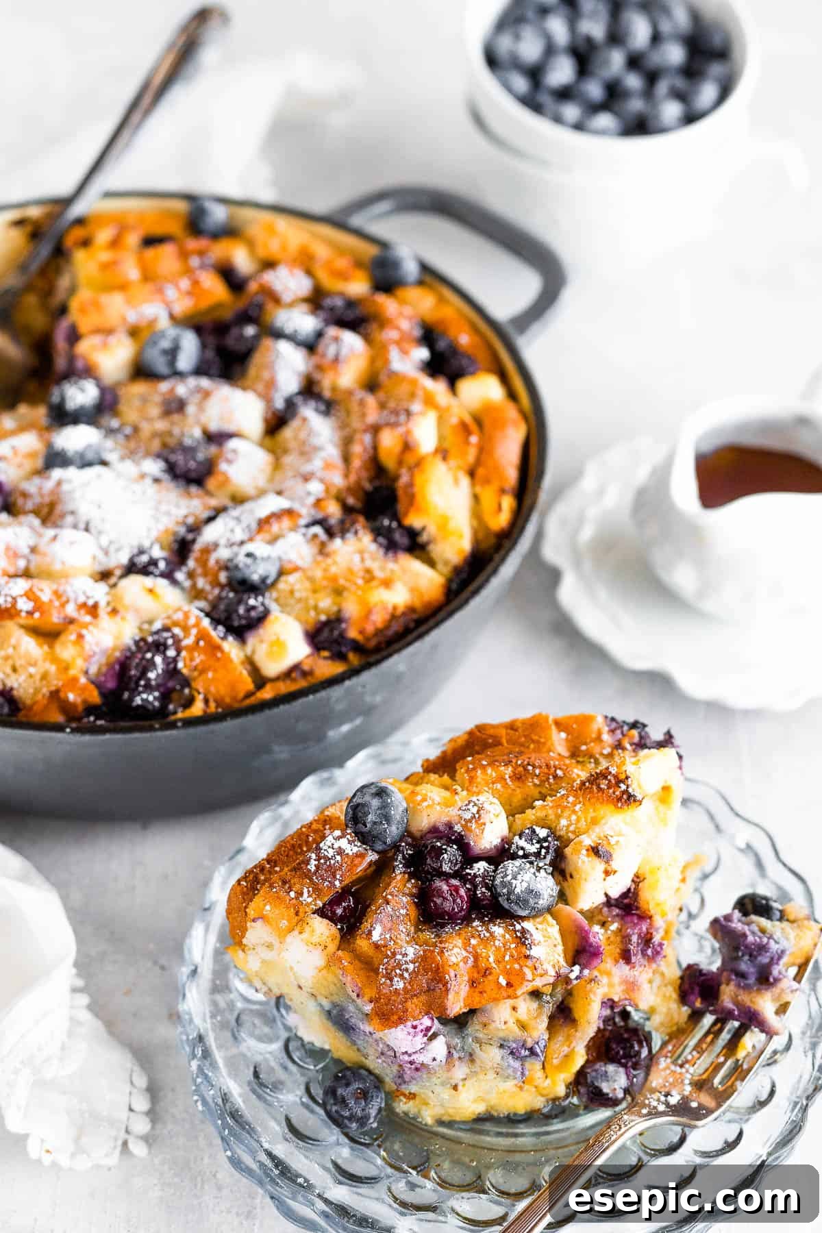A Serving of Blueberry French Toast Bake on a Plate with the Full Casserole Behind it