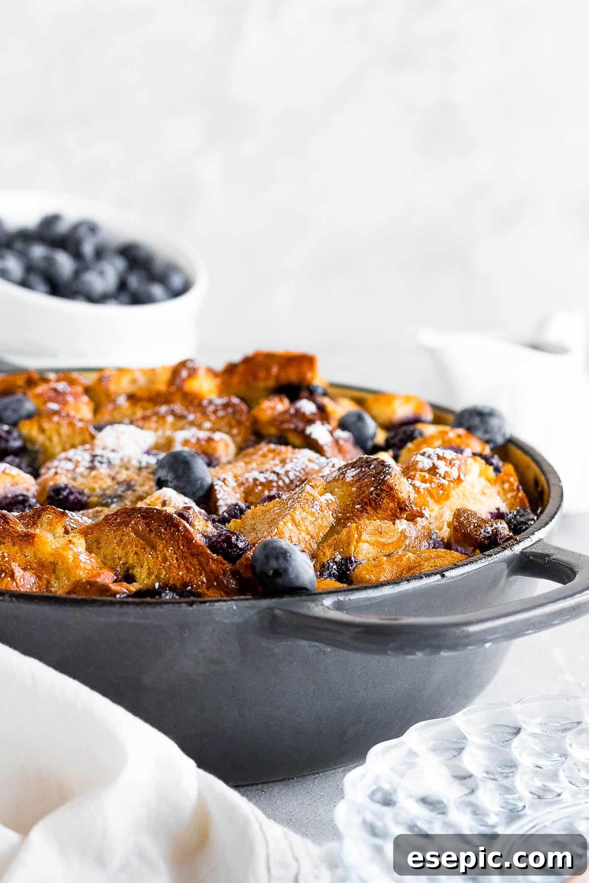 A Baked Blueberry French Toast Casserole in a Round Pan Topped with Powdered Sugar