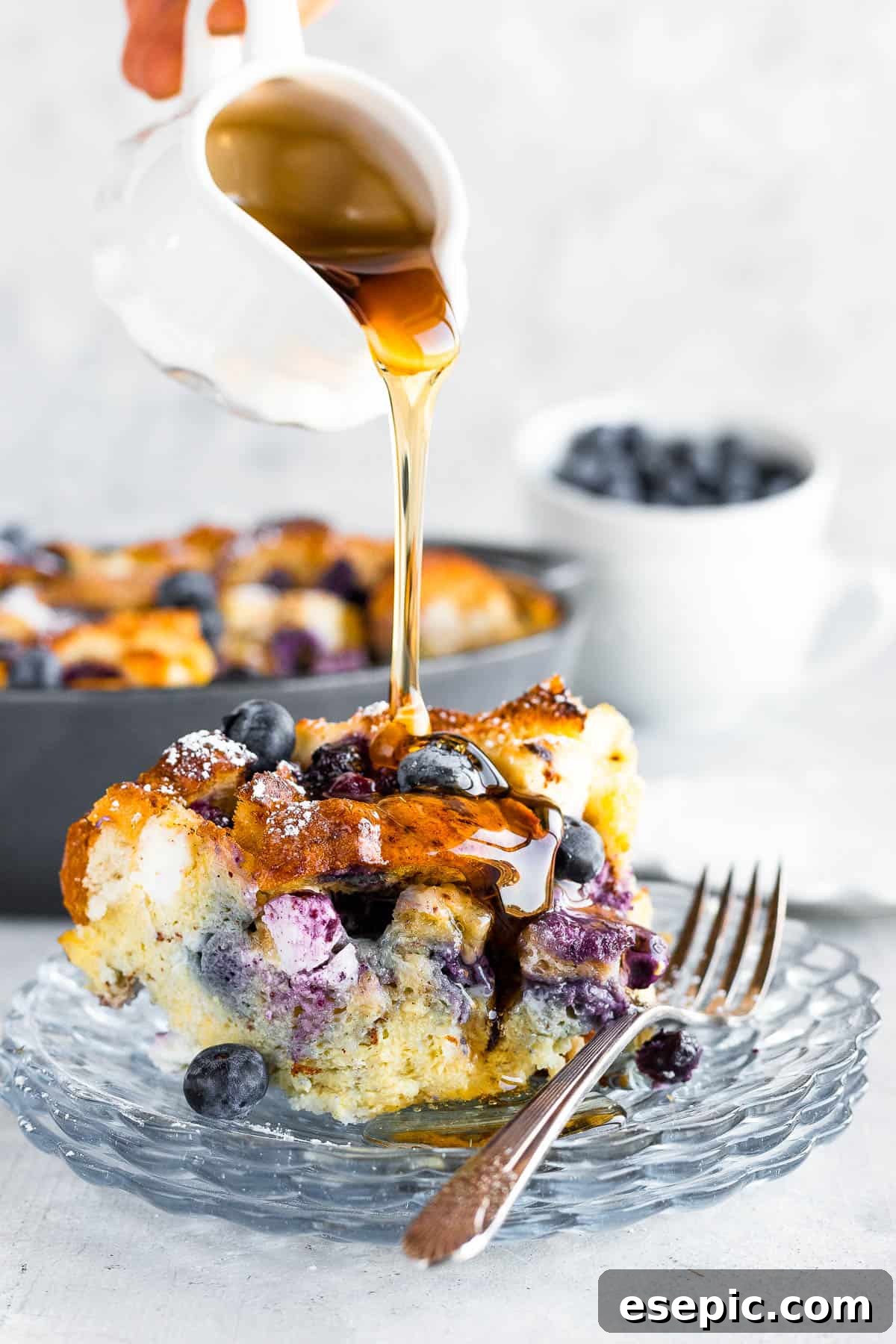 A Spouted Measuring Cup Drizzling Maple Syrup Over a Piece of French Toast Casserole