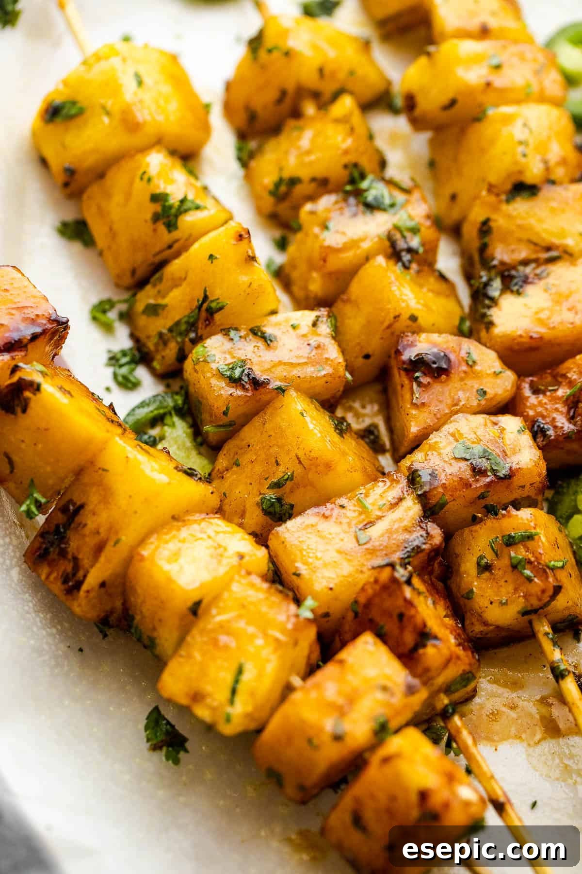 side shot of pineapple skewers topped with chopped cilantro