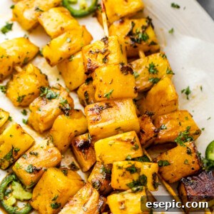 Tequila Kissed Grilled Pineapple 9 Grilled tequila pineapple skewers served on a plate, garnished with fresh cilantro.